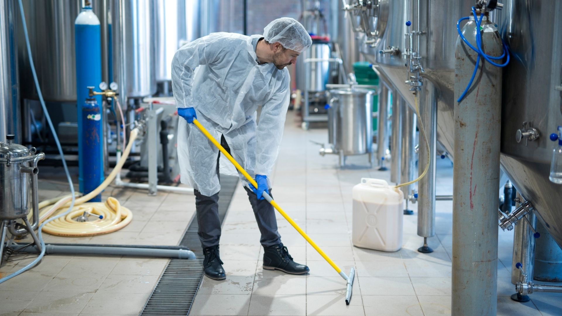 man maakt de vloer schoon in een brouwerij
