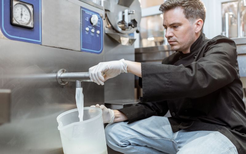 Man die melk uit een pasteurisator giet