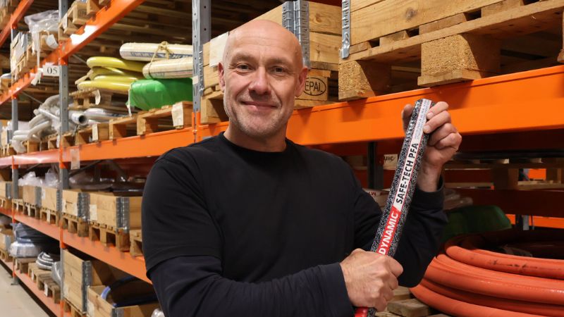 Man die een industriële slang in een magazijn vasthoudt