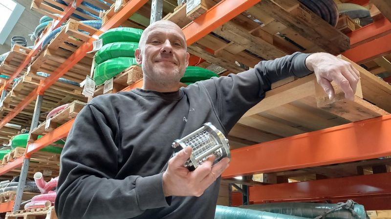 Man in een magazijn met een kijkglas in zijn hand